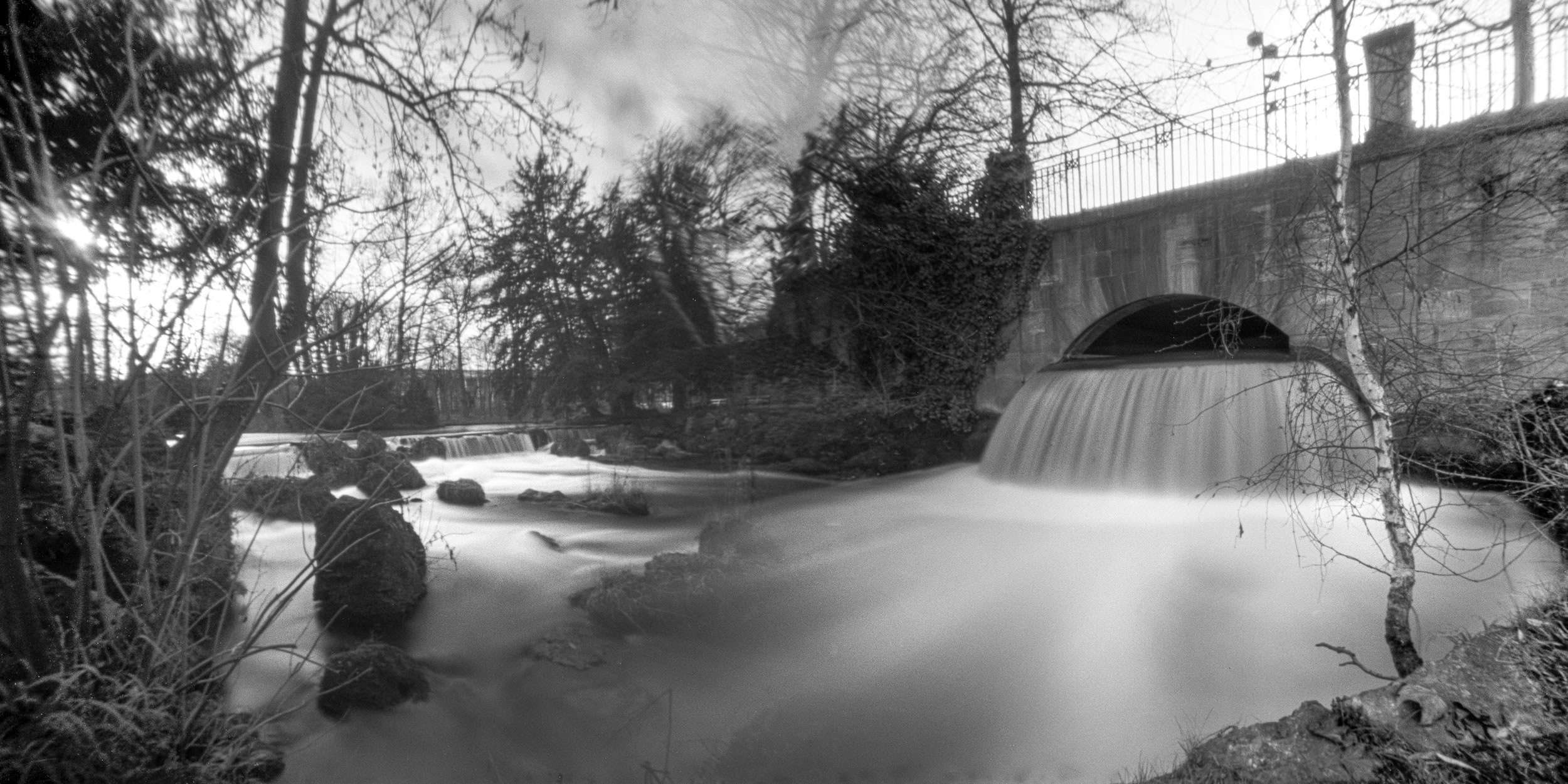 Pinhole photograph: a bridge over still water, black and white