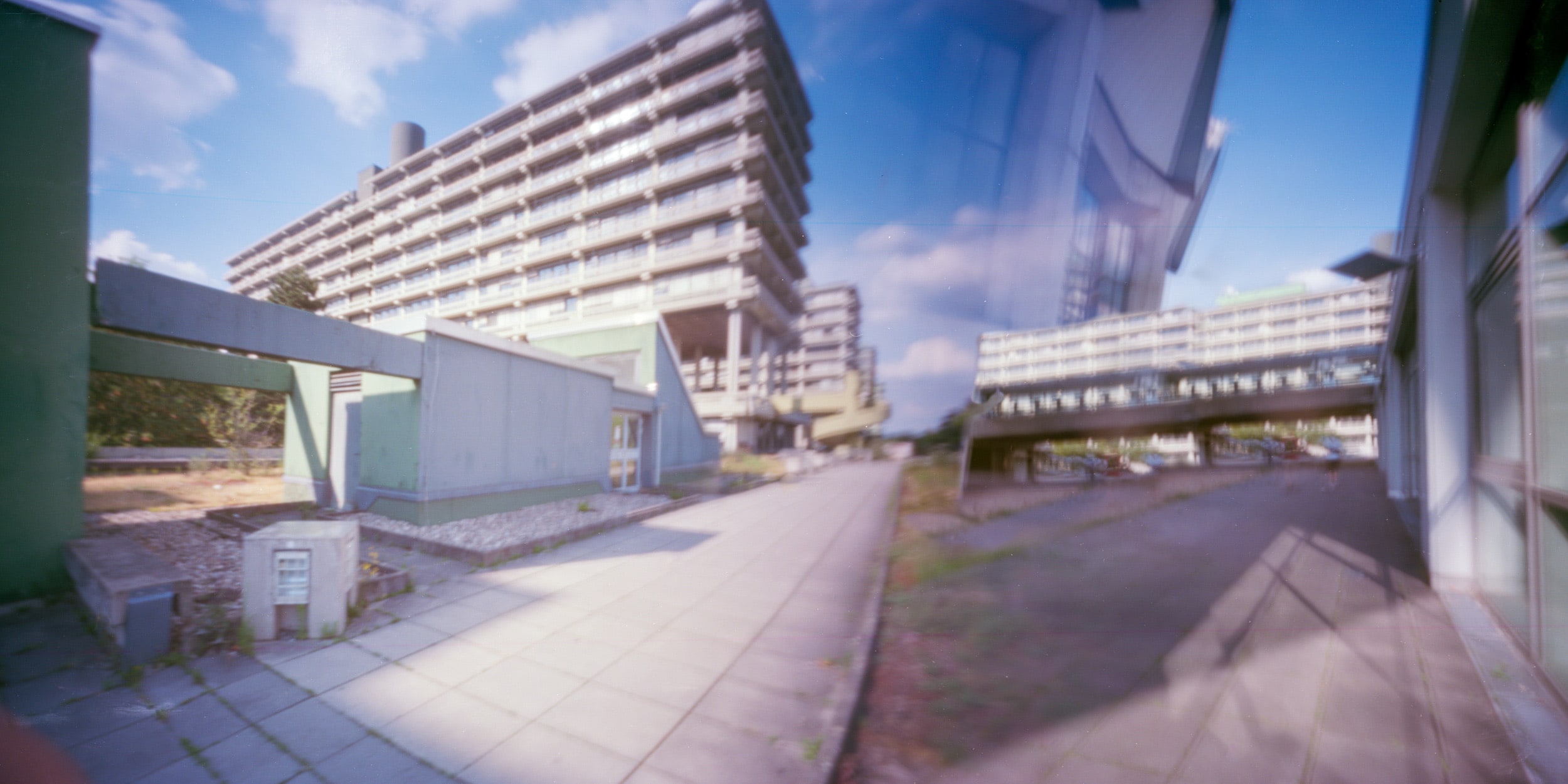 Pinhole photograph: a long low building beside an open field and trees
