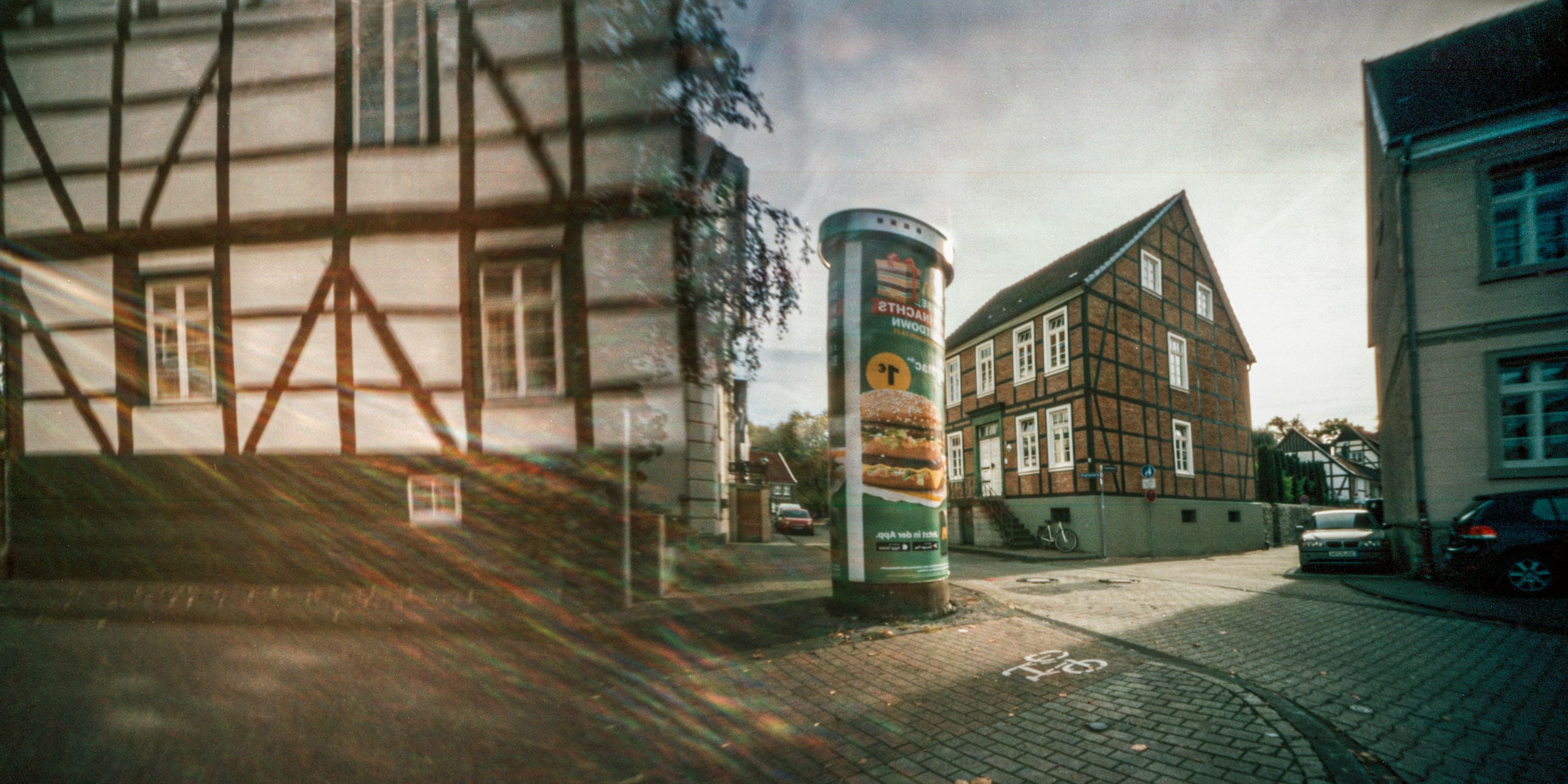 Pinhole photograph: a street corner with timber framing and an advertising column